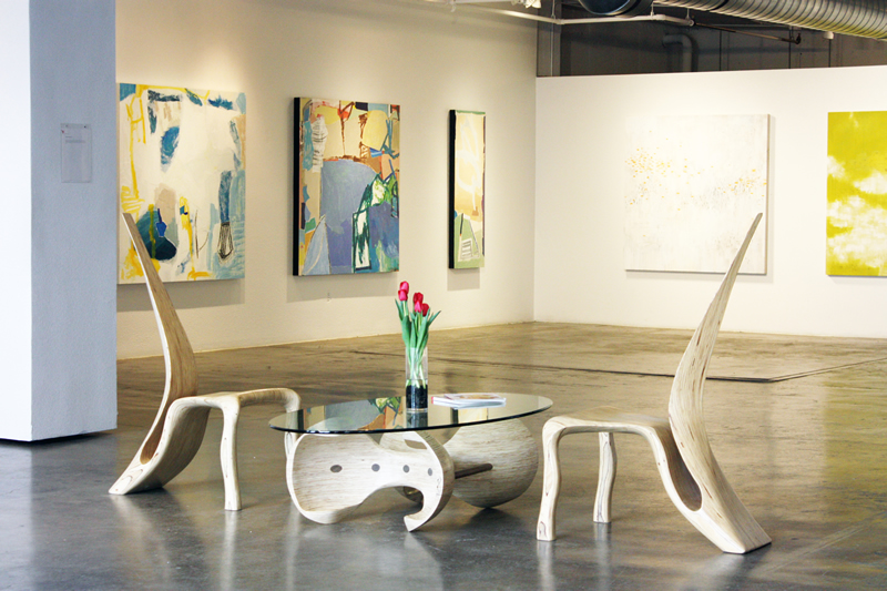 Glass top coffee table and two wood chairs in a contemporary art gallery